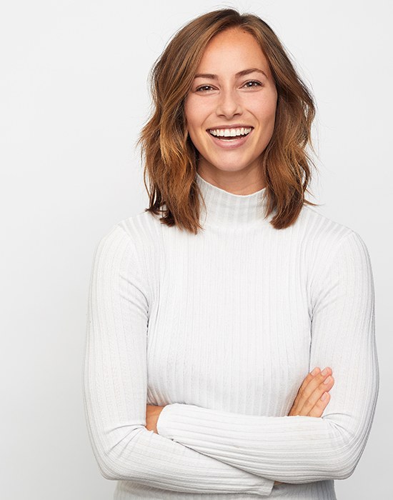 Woman in white sweater with arms crossed smiling