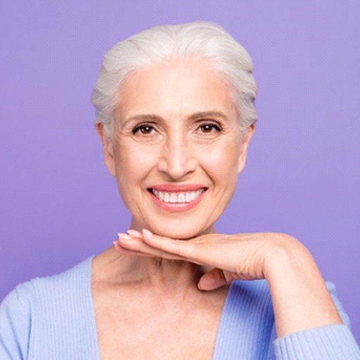 Confident woman with dentures in Fort Worth smiling on purple background
