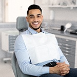 Man in blue shirt smiling while sitting in dental chair
