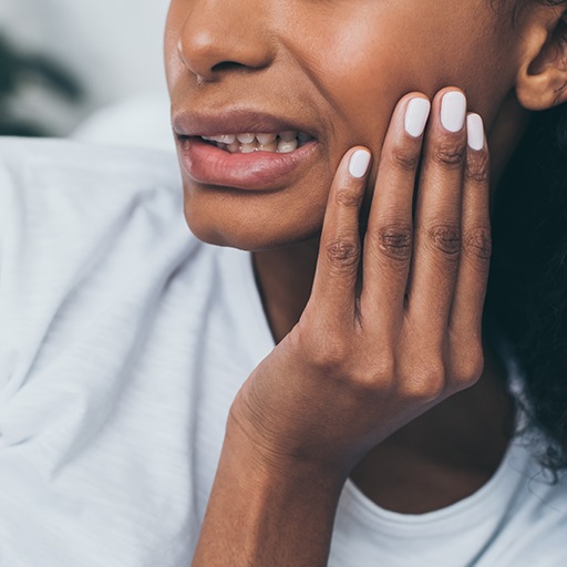 Closeup of patient in need of emergency dentistry holding jaw