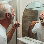 mature man brushing teeth for cost of dental implants in Fort Worth
