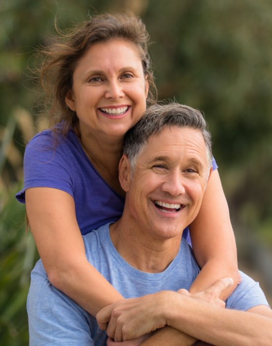 Man and woman smiling after dental implant tooth replacement