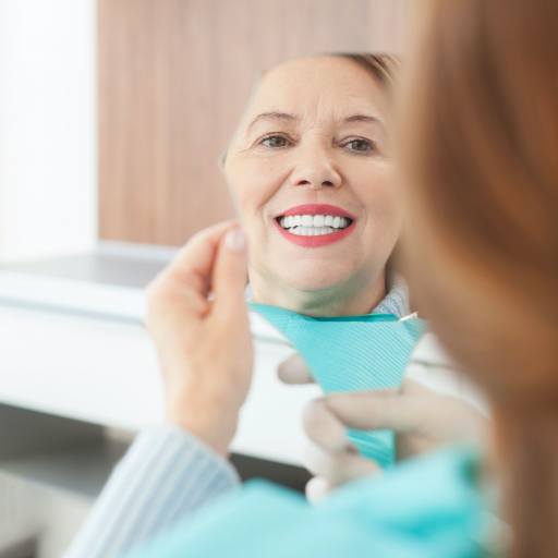 Woman looking at smile after dental implant supported replacement tooth