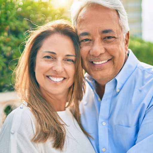 Older couple sharing healthy smiles after dental implant tooth replacement