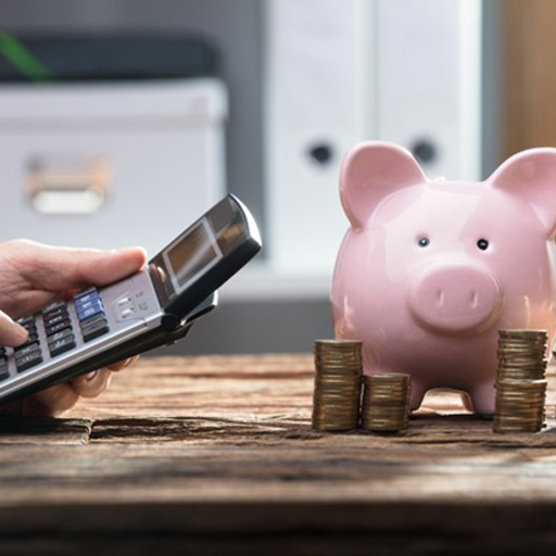 Someone operates pocket calculator by piggy bank