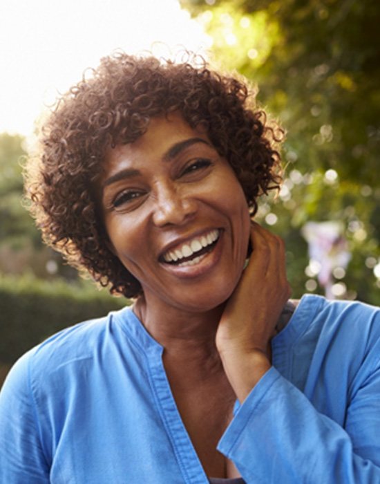 woman smiling outdoors after a full mouth reconstruction in Fort Worth