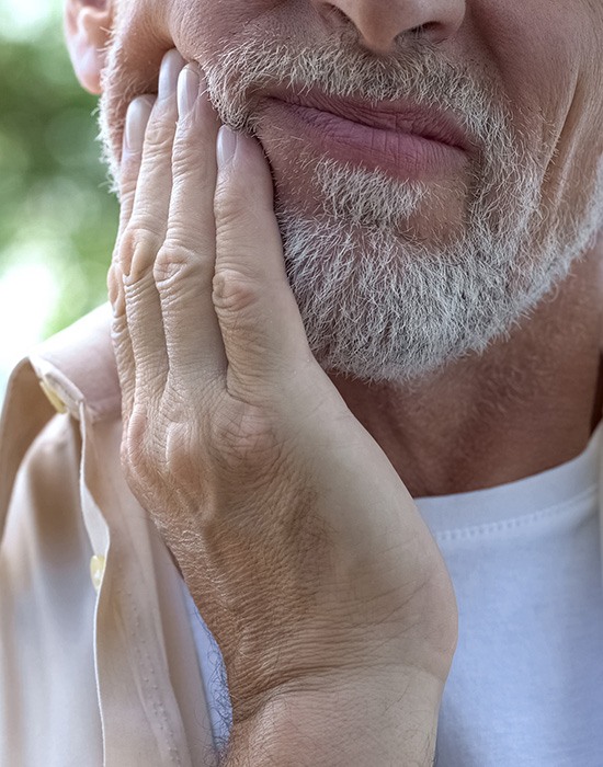 Close up of man in need of TMJ treatment in Fort Worth rubbing jaw in pain