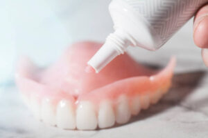 Denture adhesive being applied to upper denture