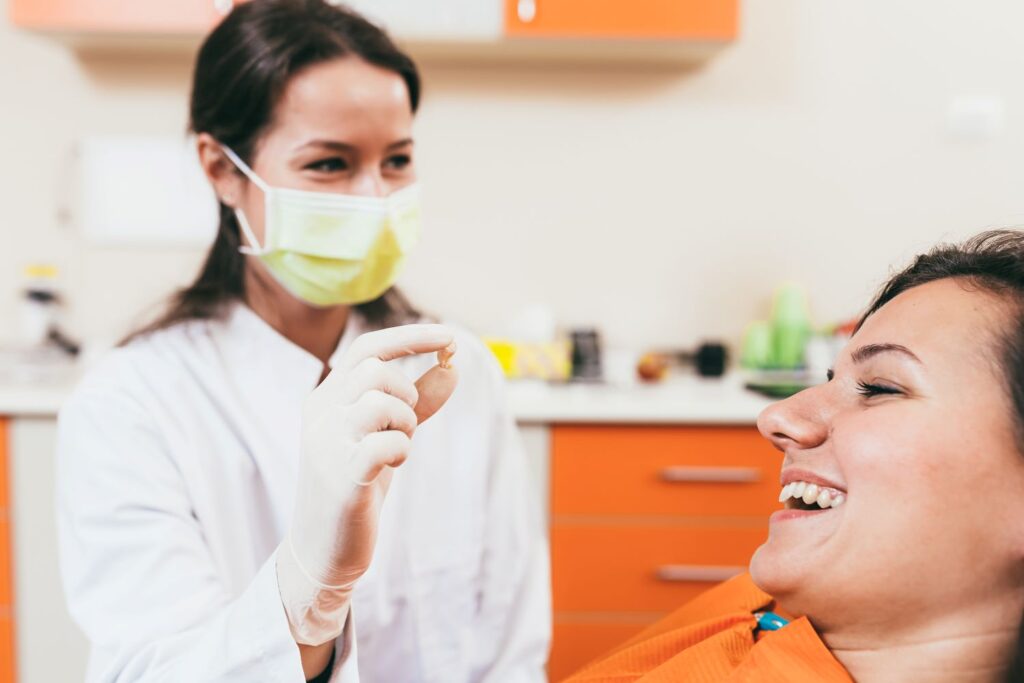 Dentist showing smiling patient her extracted tooth